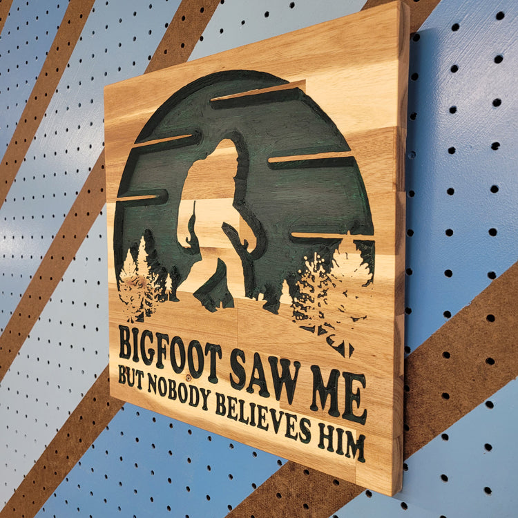 Angled shot of a Handcrafted relief-carved hardwood sign featuring a Bigfoot silhouette and the text "BIGFOOT SAW ME BUT NOBODY BELIEVES HIM."