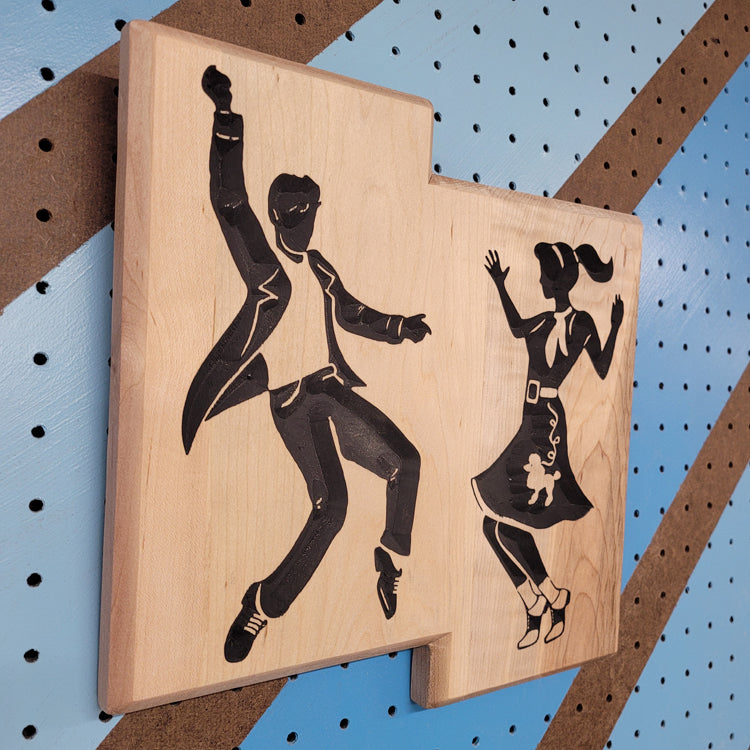 Angled shot of a custom hardwood 1950s swing dance sign with relief carved and hand-painted rockabilly jive couple.
