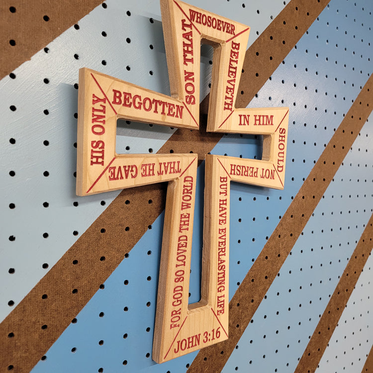 Angled shot of a Handcrafted relief-carved hardwood cross, featuring the text of John 3:16.