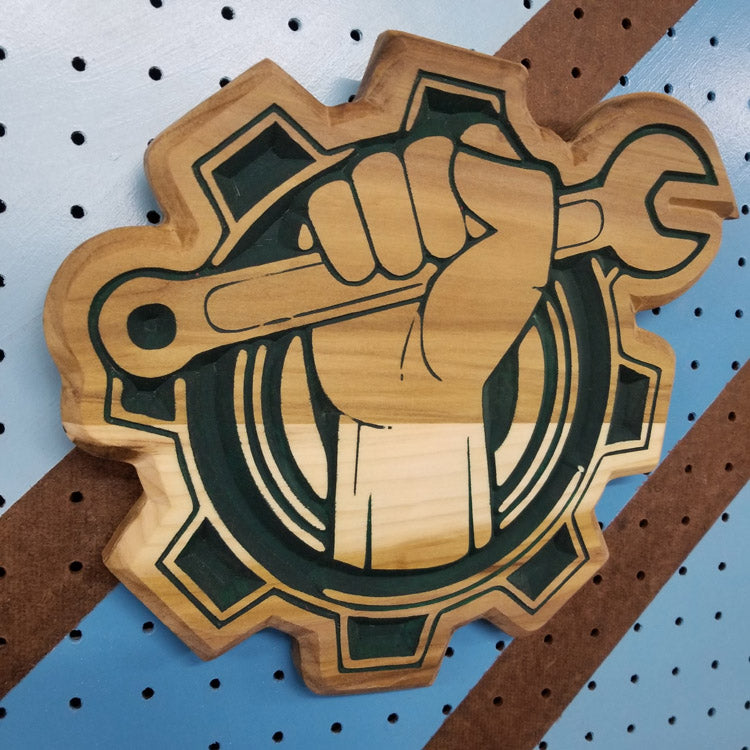 Angled shot of a Relief carved hardwood sign featuring a fist clutching a wrench in a bold, mechanic-style design.