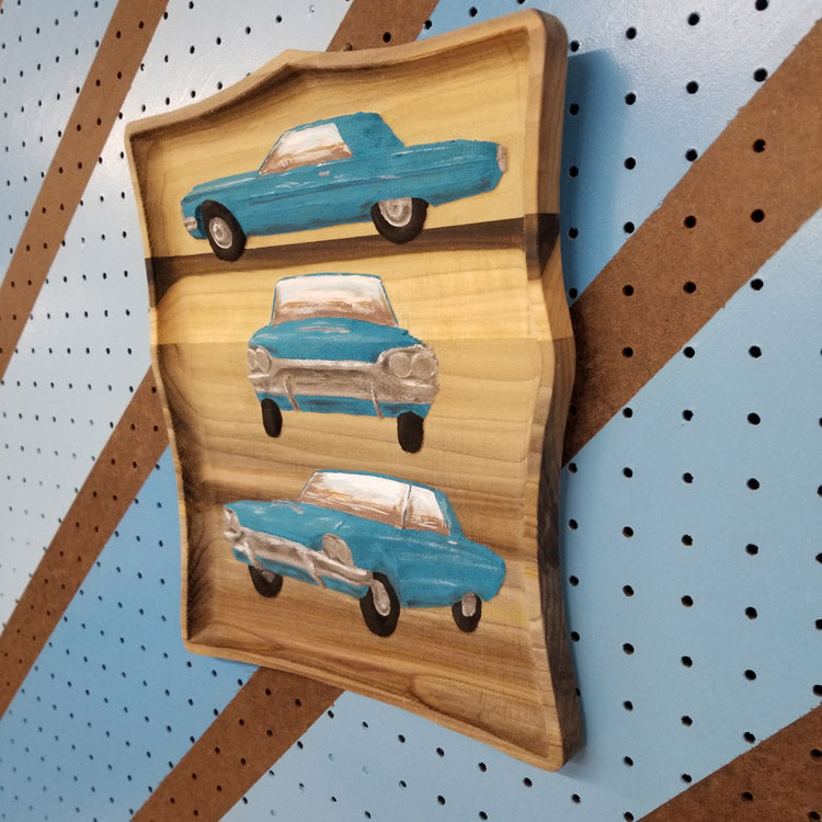 Side view showing the dimensional carving depth and hand-painted finish of a custom hardwood car sign.