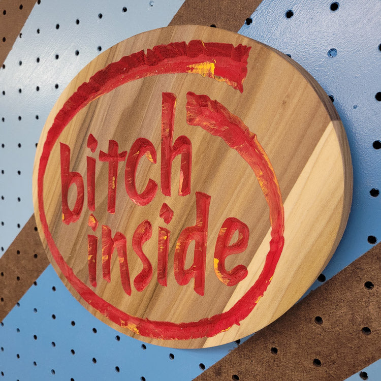Angled shot of a Handcrafted relief-carved hardwood sign featuring a design inspired by the Intel logo, with the text "Bitch Inside."