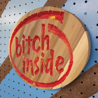 Angled shot of a Handcrafted relief-carved hardwood sign featuring a design inspired by the Intel logo, with the text "Bitch Inside."