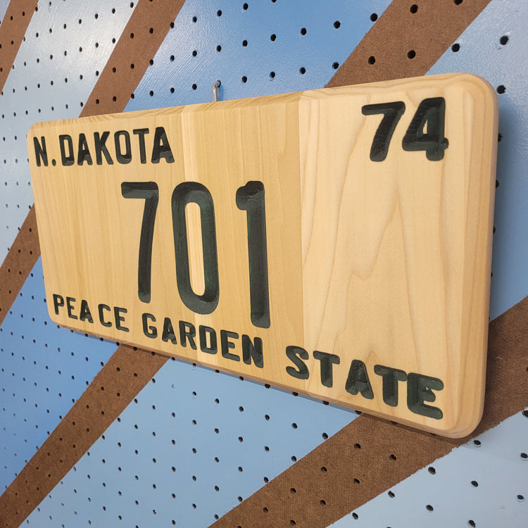 Angled shot of a Handcrafted relief-carved hardwood sign designed to look like a classic license plate, fully customizable so you can choose your own state, year, and 7-character text.