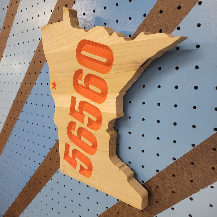 Angled shot of a Handcrafted relief-carved hardwood Minnesota sign featuring a customizable town name and zip code, allowing you to highlight your hometown with a personalized star placement.