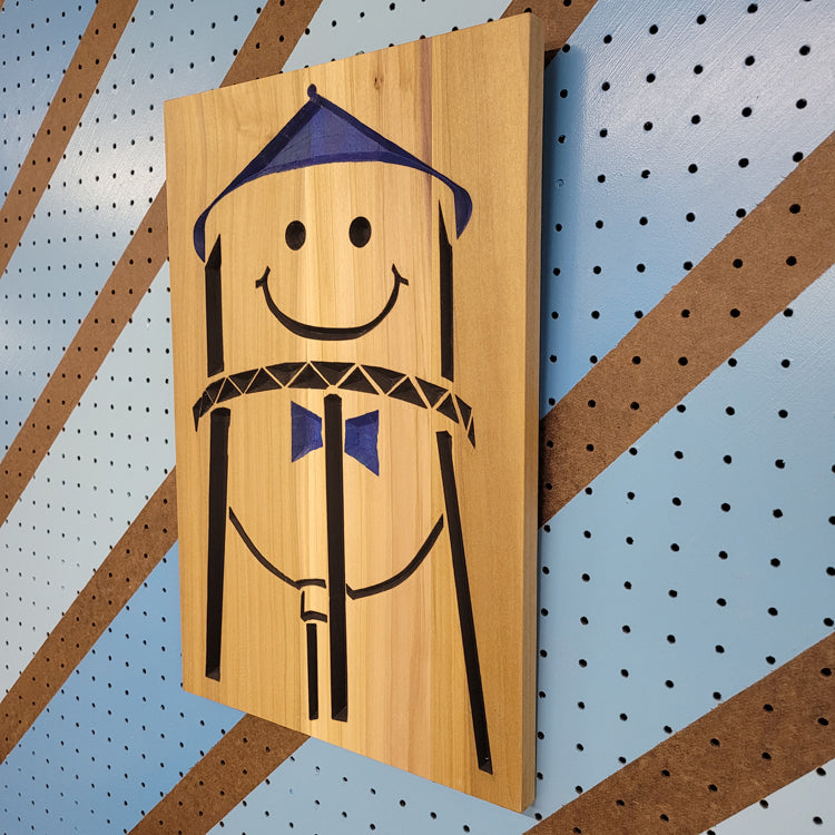 Angled shot of a relief carved hardwood sign featuring the iconic Grand Forks smiley water tower design with blue and black painted accents.