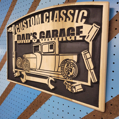 Angled shot of a Relief carved hardwood "Custom Classic Dad's Garage" sign featuring a vintage car illustration and tool motif, fully customizable to your specific vehicle.
