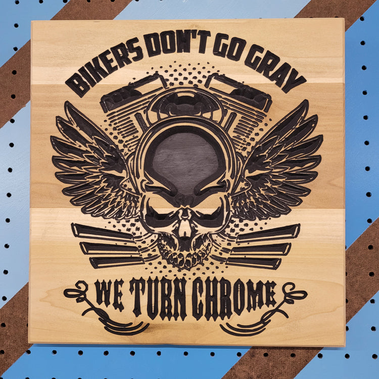 Relief carved hardwood sign featuring a winged skull with a motorcycle engine, Bikers Don't Go Gray, and We Turn Chrome text
