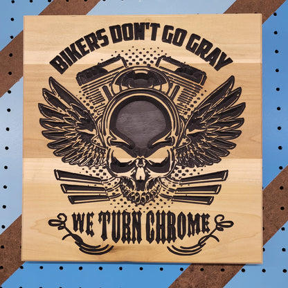 Relief carved hardwood sign featuring a winged skull with a motorcycle engine, Bikers Don't Go Gray, and We Turn Chrome text