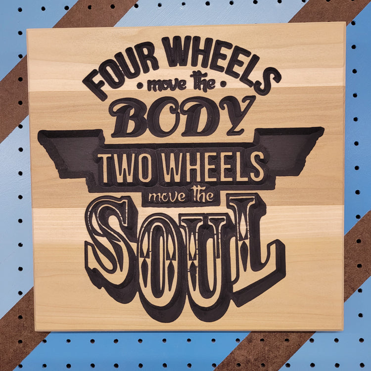 Handcrafted relief-carved hardwood sign featuring the text "Four Wheels Move The Body, Two Wheels Move The Soul."