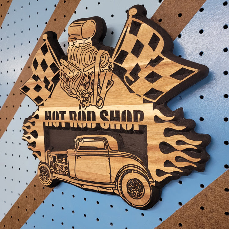High-angle shot of a relief carved hardwood sign with a 1932 Ford hot rod, black blower engine, checkered flags, and Hot Rod Shop text.