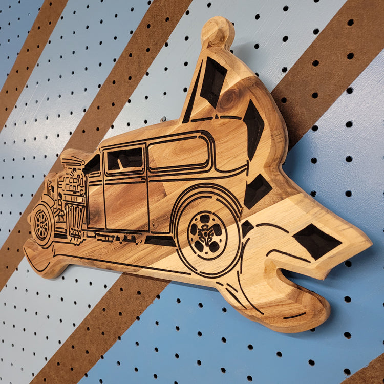 Angled shot of a carved wooden wrench flag garage sign featuring a vintage hot rod design on shop pegboard