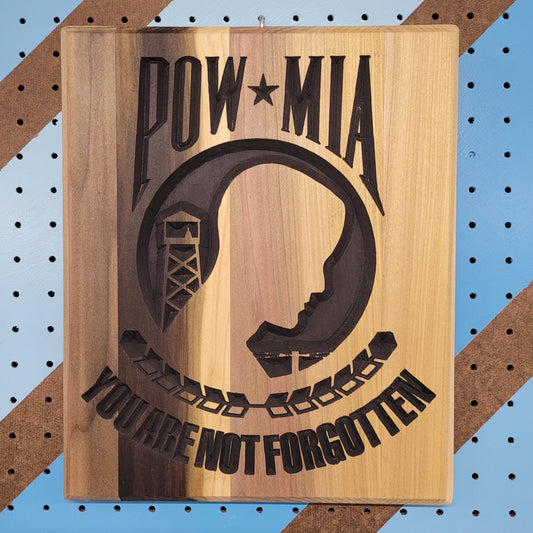 Relief carved hardwood POW MIA sign with a silhouette design and You Are Not Forgotten text on a striped pegboard.