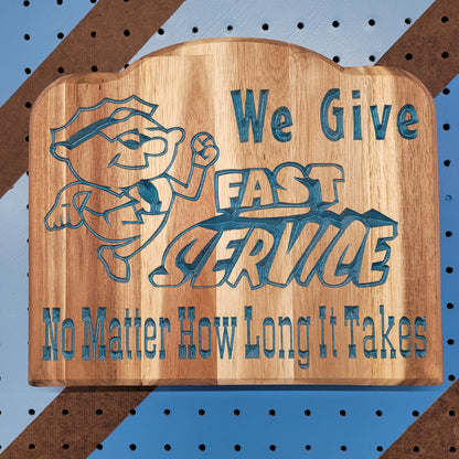 Relief carved hardwood sign featuring a cartoon mechanic and text: We Give Fast Service No Matter How Long It Takes.