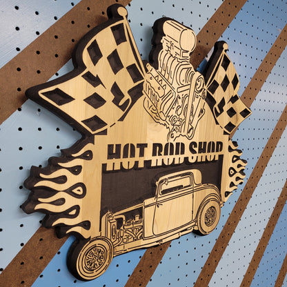 High-angle shot of a relief carved hardwood sign with a 1932 Ford hot rod, black blower engine, checkered flags, and Hot Rod Shop text.