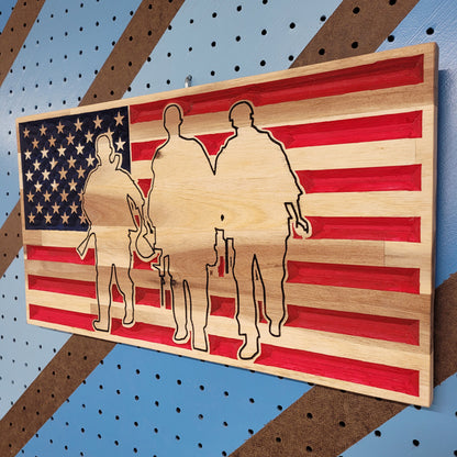Angled shot of a relief carved hardwood American flag sign featuring a precision-cut silhouette of three soldiers on a pegboard.