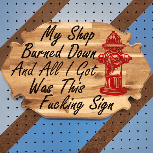 Custom hardwood sign with relief carved red fire hydrant and My Shop Burned Down text on a striped pegboard.