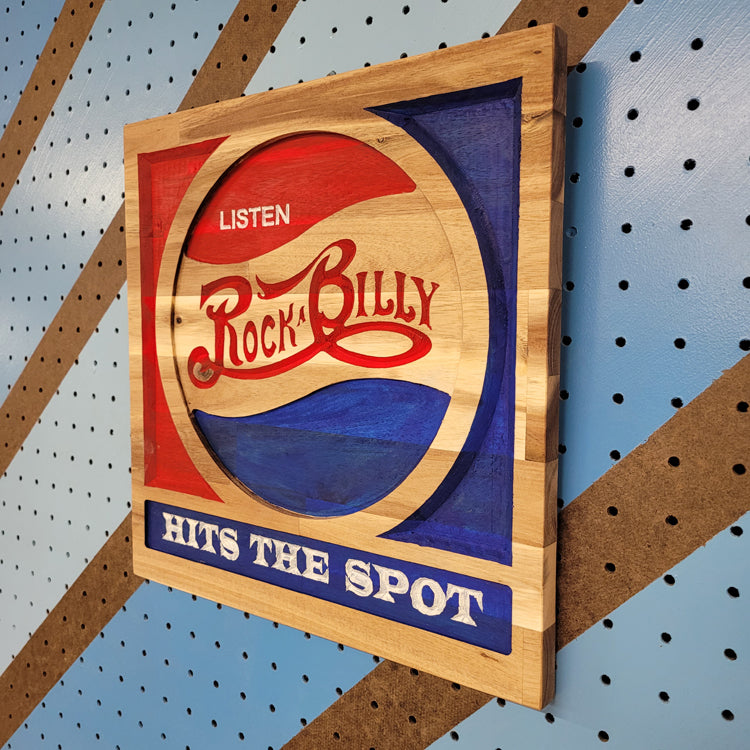 Angled shot of a relief carved hardwood sign with red and blue retro soda parody design, Listen Rockabilly Hits the Spot text.