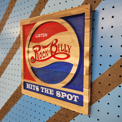 Angled shot of a relief carved hardwood sign with red and blue retro soda parody design, Listen Rockabilly Hits the Spot text.