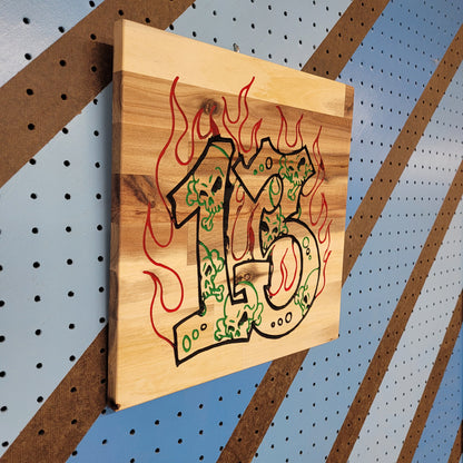 Angled shot of a Handcrafted relief-carved hardwood sign featuring the number "13" stylized with skulls and flames.