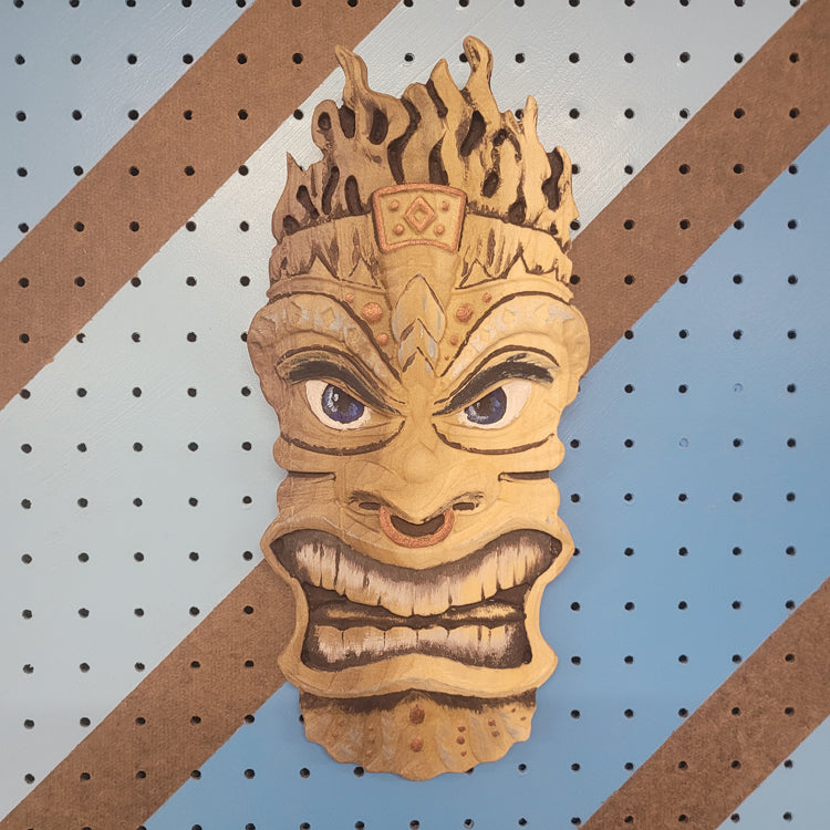 3D relief carved hardwood Tiki totem sign with unique hand-painted details on a blue pegboard.