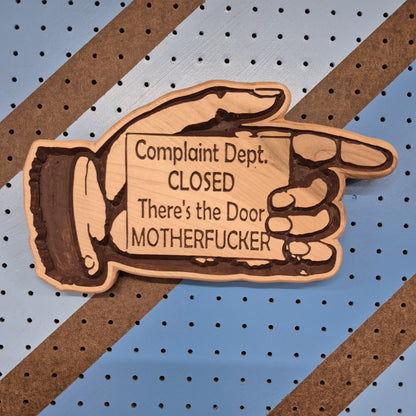 Handcrafted relief-carved hardwood sign in the shape of a hand pointing, featuring the text "Complaint Dept. CLOSED There's the Door."