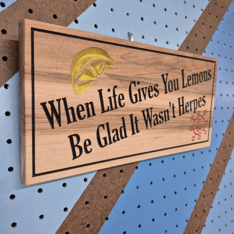 Angled shot of a relief carved hardwood sign featuring a lemon illustration, virus graphic, and When Life Gives You Lemons Be Glad It Wasn't Herpes text.
