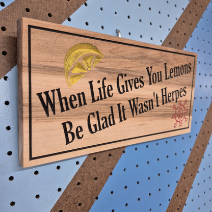 Angled shot of a relief carved hardwood sign featuring a lemon illustration, virus graphic, and When Life Gives You Lemons Be Glad It Wasn't Herpes text.