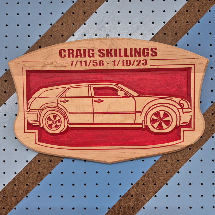 Custom CNC-carved wooden memorial plaque featuring a station wagon silhouette and the text 'Craig Skillings 7/11/58 - 1/19/23'