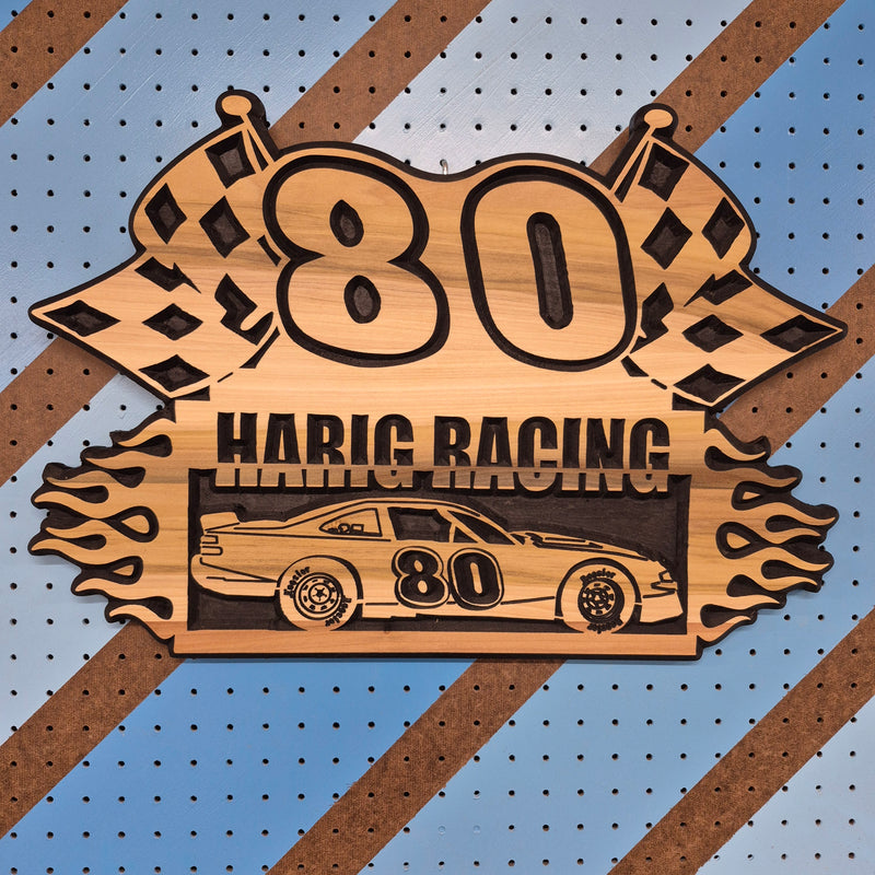 Custom CNC-carved wooden sign for 'Harig Racing,' featuring checkered flags and race car silhouettes, handcrafted and finished by Whiskey River Craftworks.