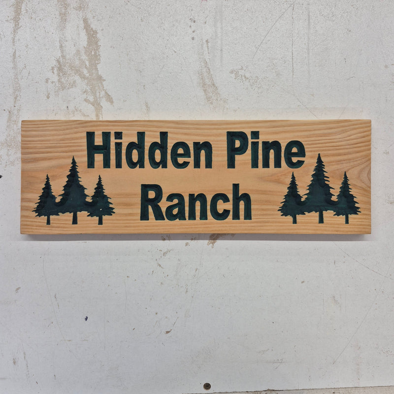 Custom CNC-carved wooden sign for Hidden Pine Ranch, featuring pine tree silhouettes and hand-finished detail by Whiskey River Craftworks