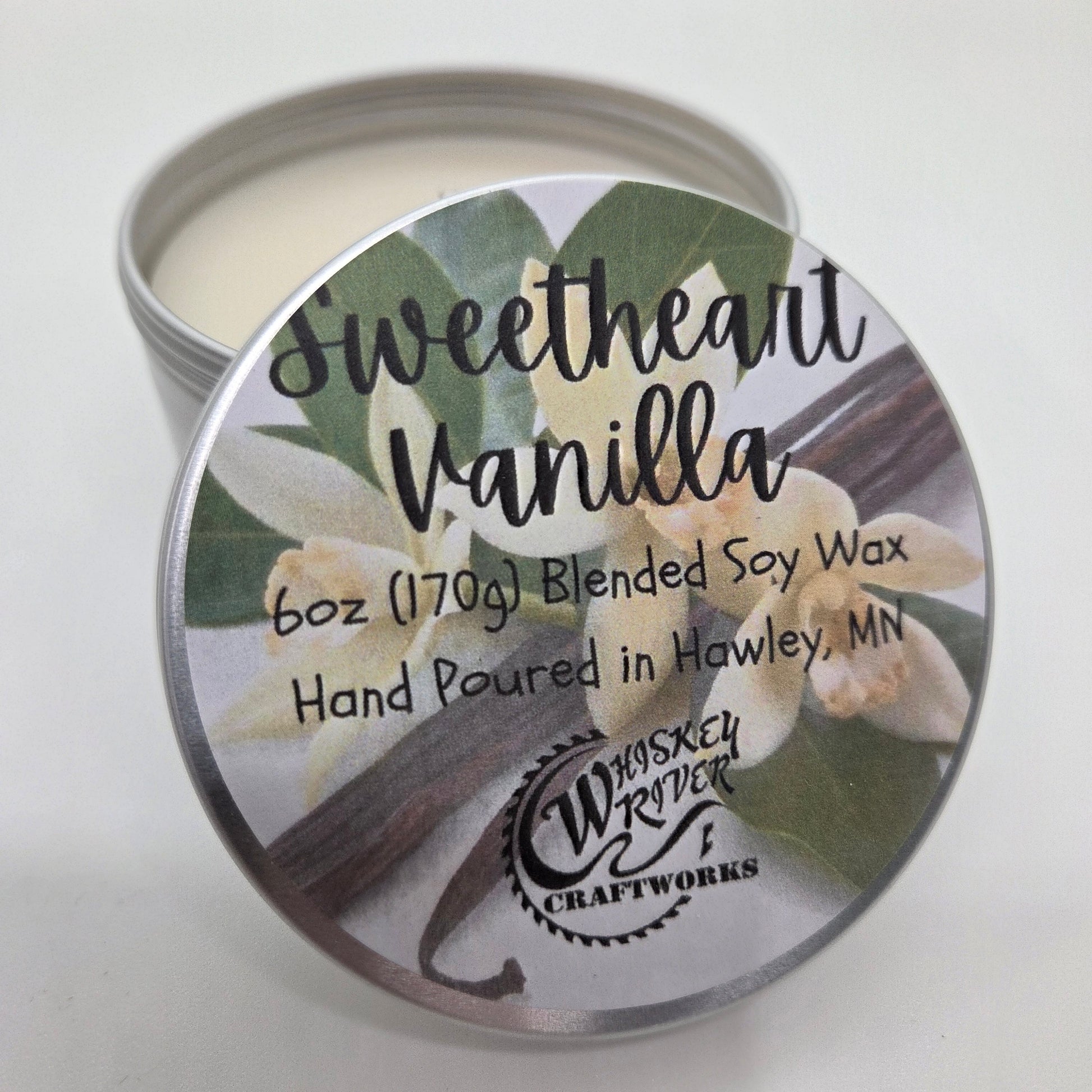 Candle tin labeled 'Sweetheart Vanilla' with floral design on a white background