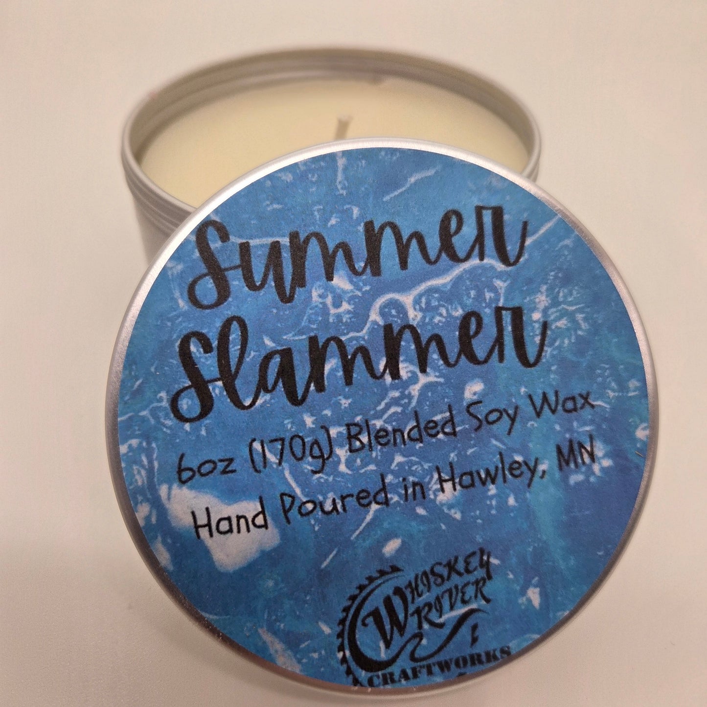 Candle with a blue label reading 'Summer Slammer' on a beige background