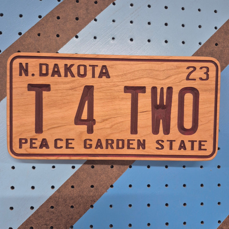 Custom CNC-carved wooden sign designed like a vehicle license plate, featuring the text 'N. Dakota 23', 'T 4 TWO', and 'Peace Garden State'.