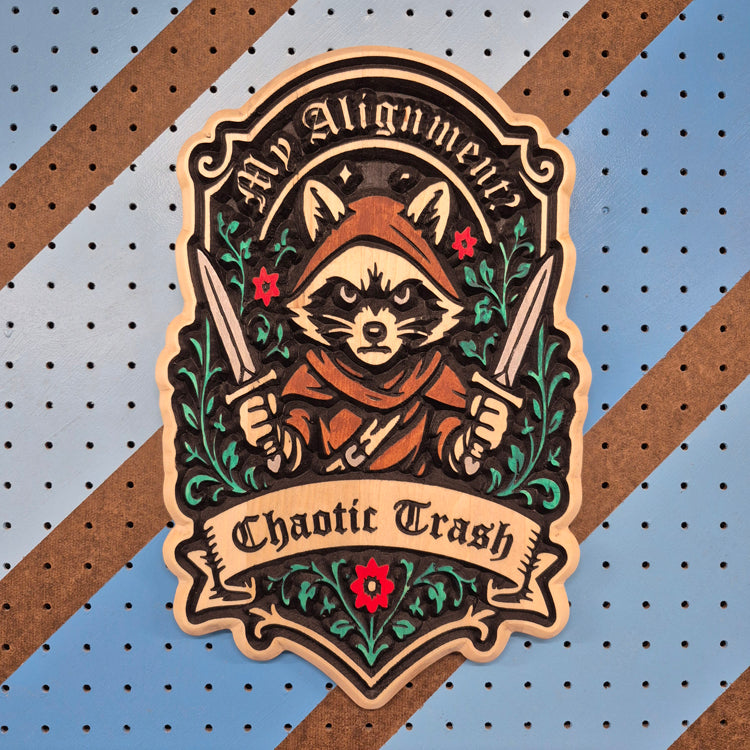 A vertical solid hardwood carved sign featuring a detailed fantasy raccoon character wearing a hooded cloak and holding twin daggers. The banner text reads "Chaotic Trash" below a circular frame with the words "My Alignment Is".