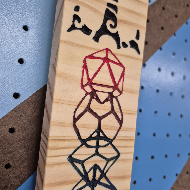 A tight close-up shot of the Dice Sword carving, highlighting the precise engraving on the hilt, the clean numbers on the embedded polyhedral dice, and the smooth, professional finish of the wood.