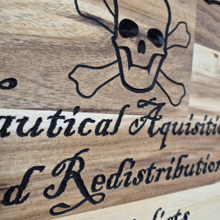 A tight close-up shot focusing on the top section of the carving, highlighting the detailed skull and crossbones artwork and the prominent "Nautical Acquisition" text.