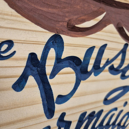 A tight close-up shot focusing on the carved lettering of the "Busty Barmaid" hardwood sign, showcasing the crisp depth of the CNC machining and the precise hand-painted dark blue paint filling the background cuts against the smooth natural wood grain.
