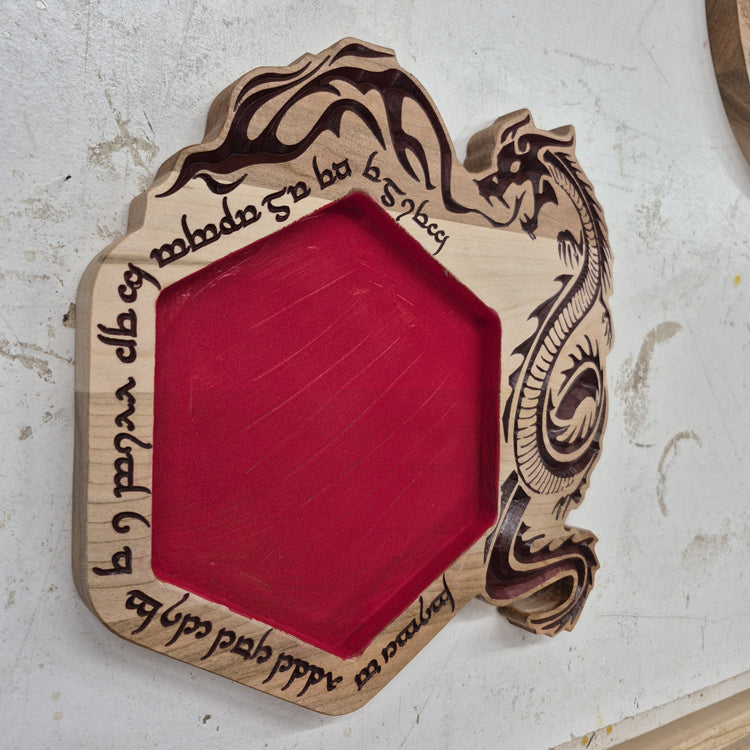 An angled side shot of the hexagonal Runic Dragon wooden dice tray, highlighting the clean depth of the runic carvings and the sharp contrast of the hand-painted dark brown details against the natural hardwood grain.
