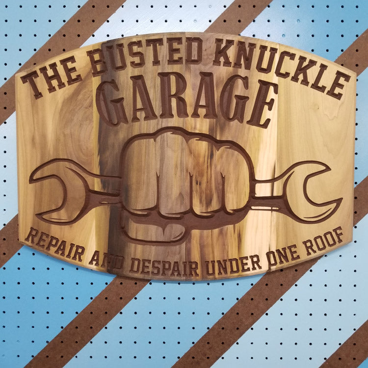 Relief carved hardwood sign featuring the text: "The Busted Knuckle Garage: Repair and Despair Under One Roof."