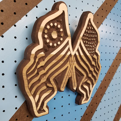 Angled shot of a Handcrafted relief-carved hardwood sign in the shape of crossed American flags.