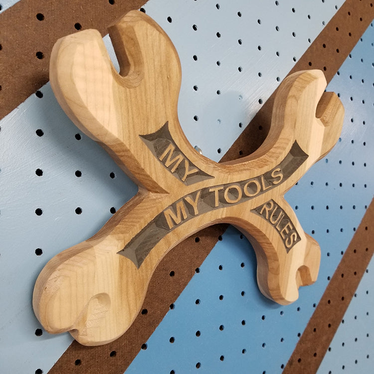 Angled shot of a Handcrafted relief-carved hardwood sign in the shape of crossed wrenches, featuring the text "My Tools My Rules.