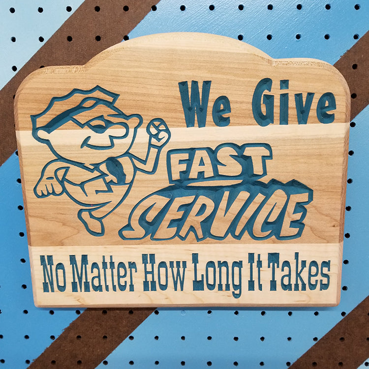 Relief carved hardwood sign featuring a cartoon mechanic and text: We Give Fast Service No Matter How Long It Takes.