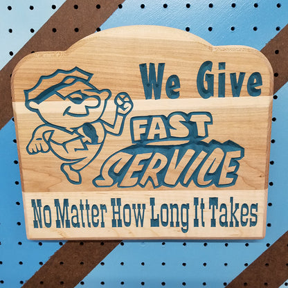 Relief carved hardwood sign featuring a cartoon mechanic and text: We Give Fast Service No Matter How Long It Takes.
