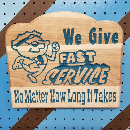 Relief carved hardwood sign featuring a cartoon mechanic and text: We Give Fast Service No Matter How Long It Takes.