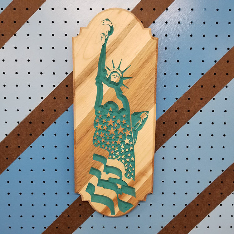 Relief carved hardwood flag sign featuring a detailed Statue of Liberty profile with a star-spangled backdrop painted teal
