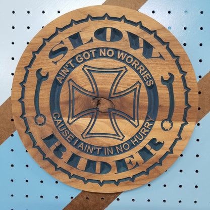 Relief carved hardwood Slow Rider biker sign with cross and wrench details on a blue pegboard