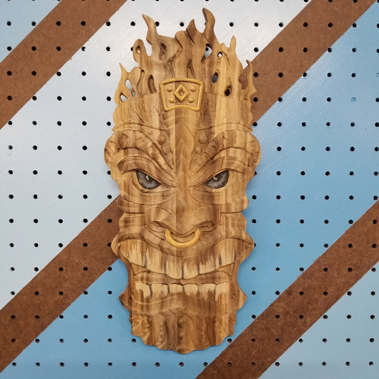 3D relief carved hardwood Tiki totem sign with unique hand-painted details on a blue pegboard.