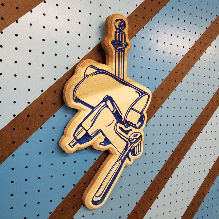 Angled shot of a custom hardwood garage sign with a carved relief design of a muffler, shock absorber, ratchet, and impact gun.