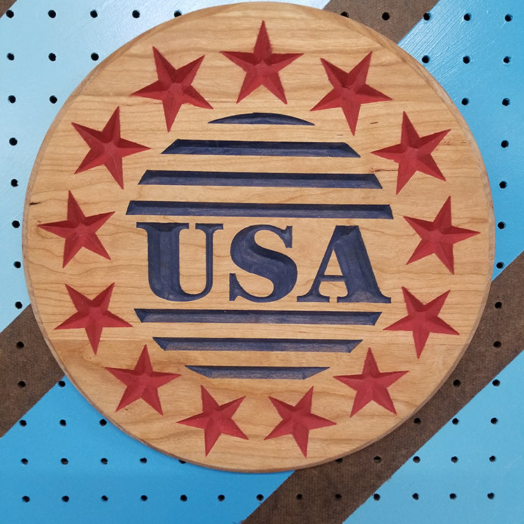 Custom hardwood USA Circle patriotic sign with a carved ring of stars and center relief text on a blue pegboard.